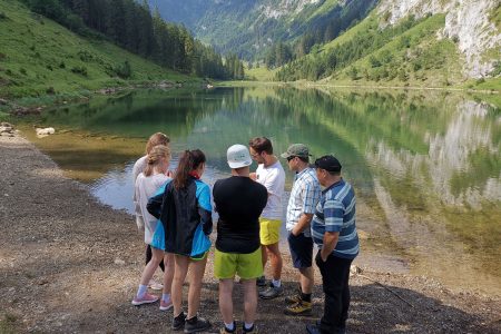 A Zurich Hiking Group standing infront of a lake in the middle of the Swiss Alps